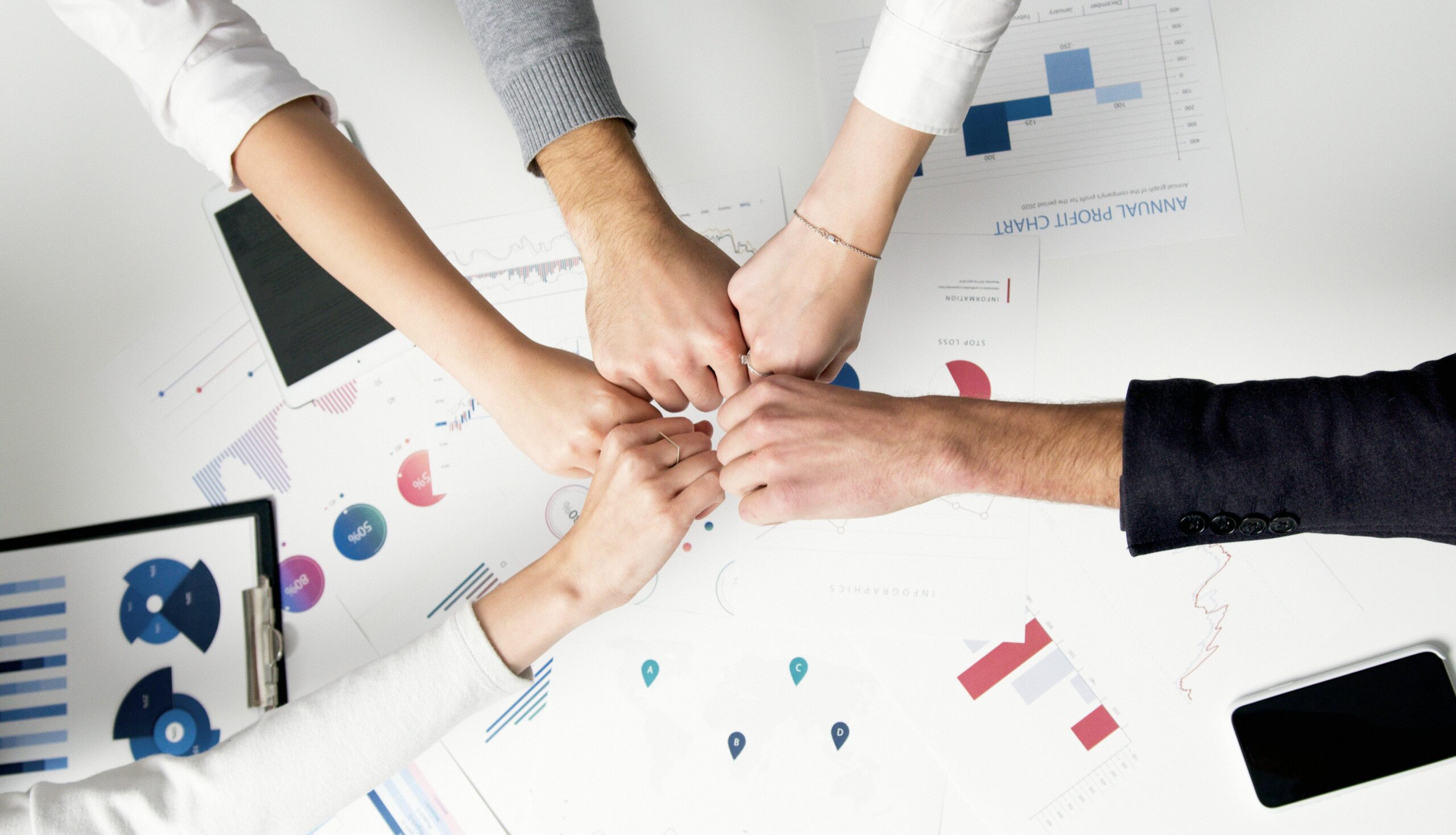 How-Smart-IT-Boosts-Employee-Morale-and-Keeps-Your-Best-People-scaledjpg Free Colleagues celebrate success with a fist bump over financial charts depicting teamwork and unity. Stock Photo